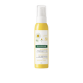 A bottle of Klorane hair treatment with a yellow label and a white spray nozzle, indicating it is a hair care product.