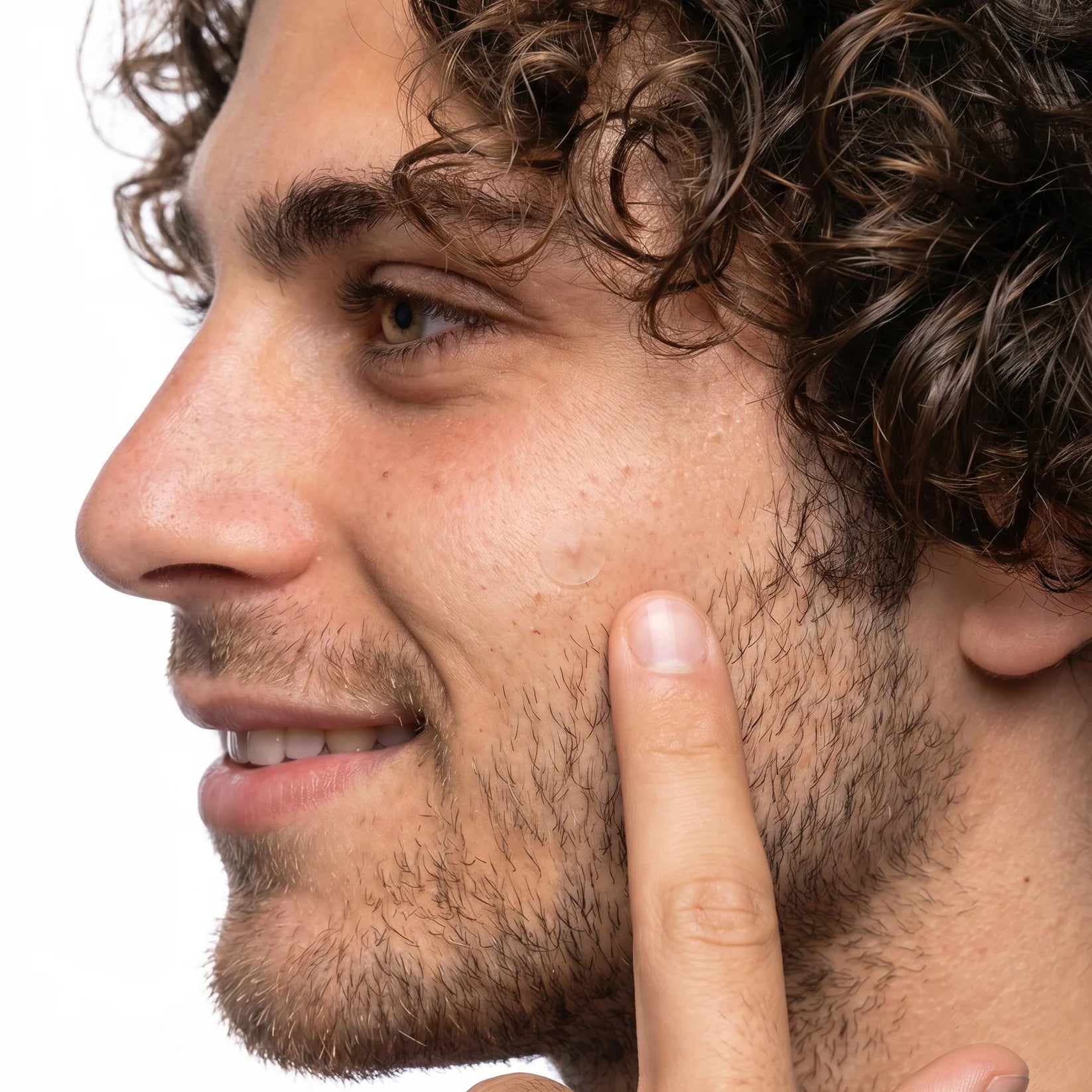 Close-up of a man with curly hair pointing to his cheek